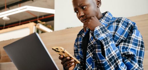 thoughtful black woman using smartphone and laptop