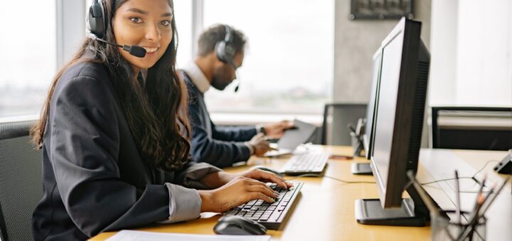a smiling woman working in a call center while looking at camera